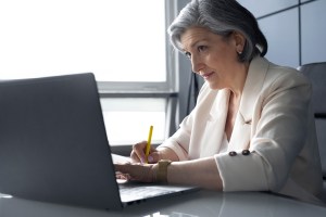 woman with grey hair working on a laptop